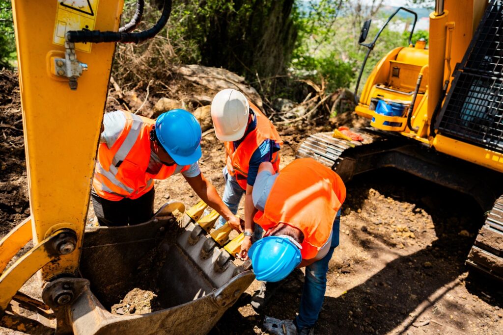 Construction workers inspecting excavator 